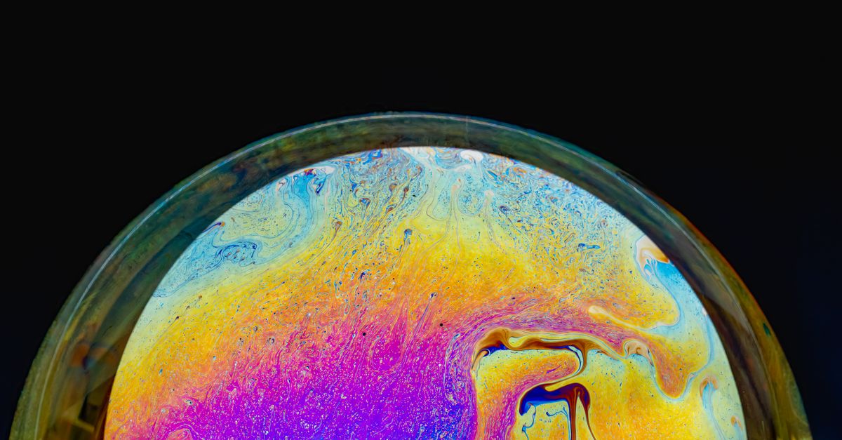 Macro shot of a colorful soap bubble displaying an iridescent spectrum against a black background.